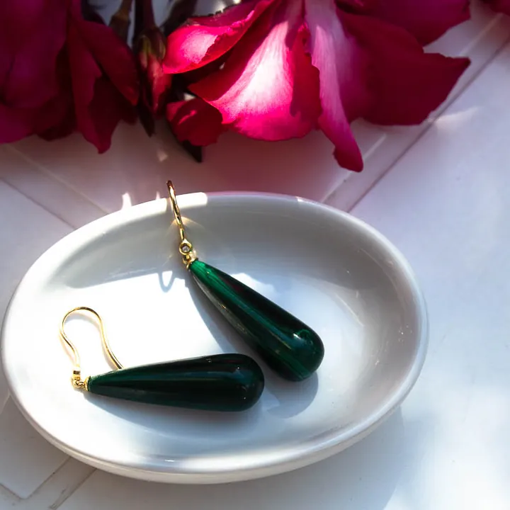 Boucles d’oreilles en gouttes de pierre verte sur or jaune, dans une coupelle blanche