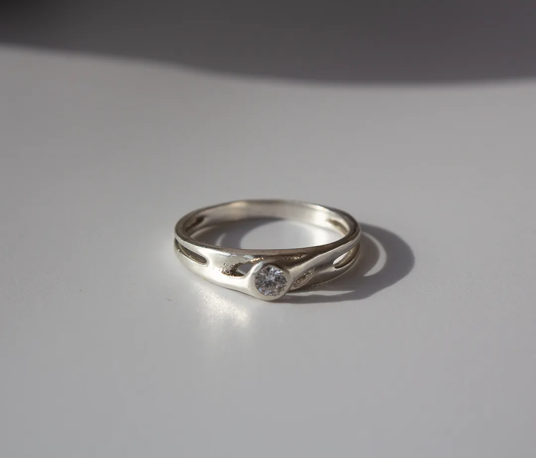 Bague ajourée en métal blanc, pierre blanche sertie