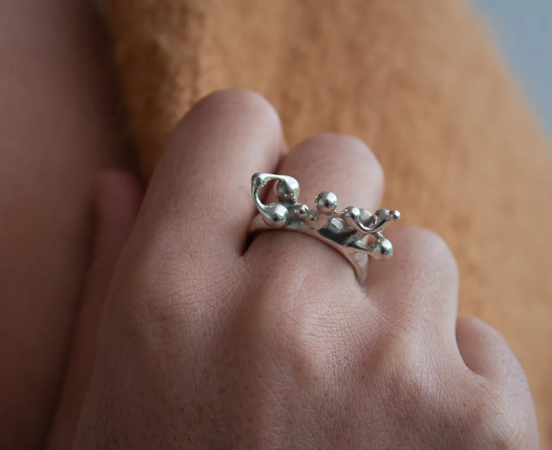 Bague ornée de petites billes, portée à la main