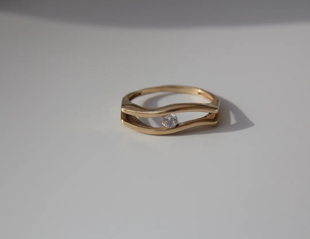 Bague en or jaune à deux anneaux ondulés, pierre blanche sertie