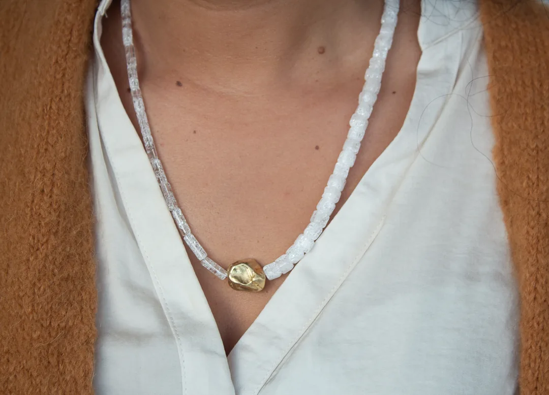Collier de perles blanches et pièce centrale dorée, porté